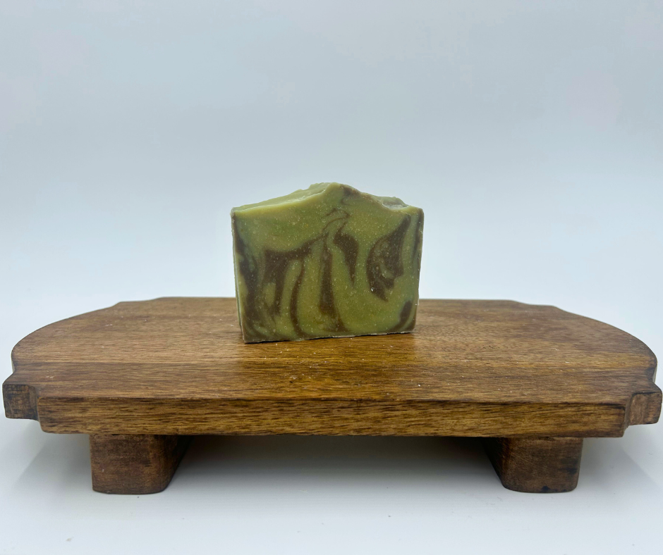 One green and brown goat milk soap on a brown stand 
