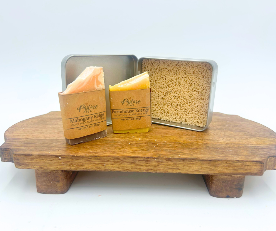 Two bars of soap on a wooden stand with branded packaging against a white background