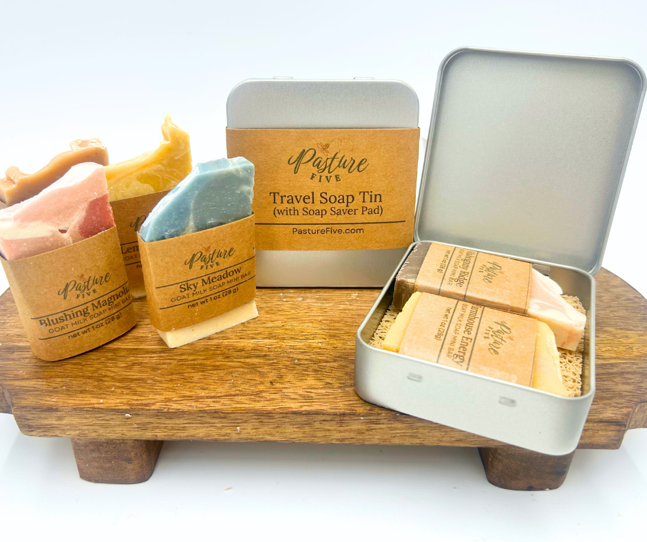Pasture Fire soap products including bars and a travel soap tin on a wooden stand.