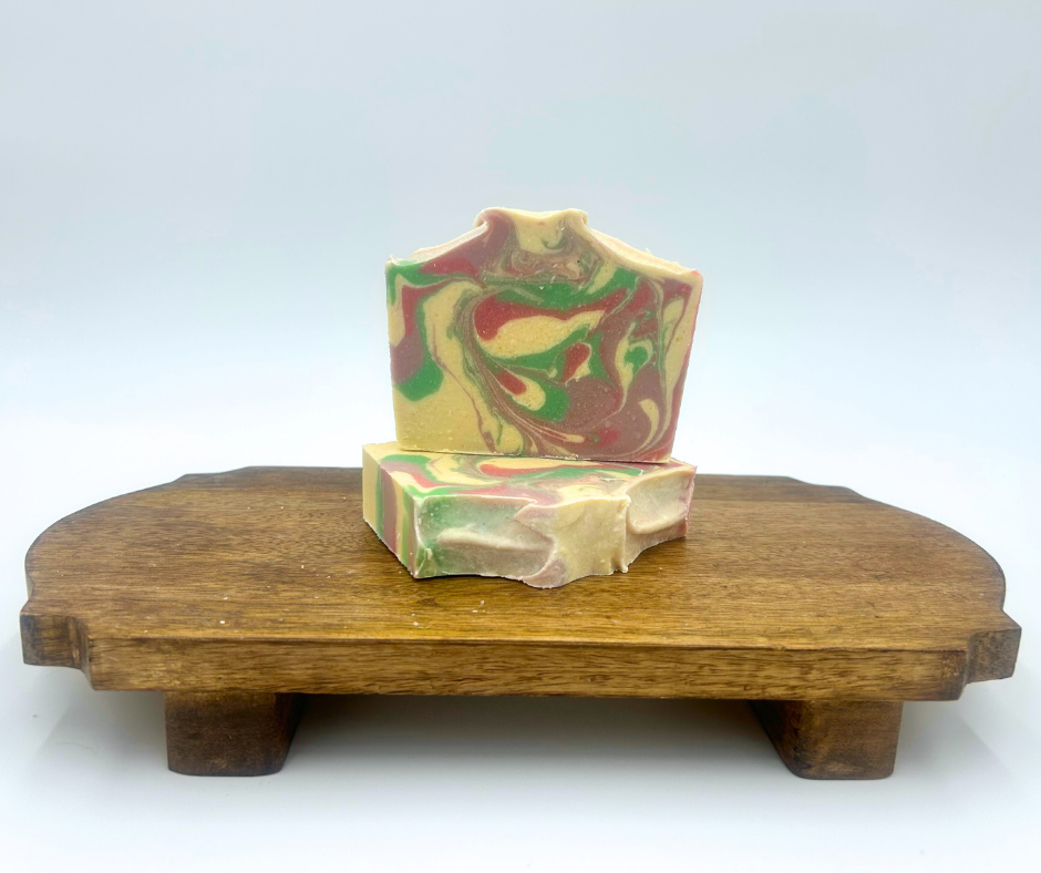 Two Wildflower Meadow Goat Milk soap bars on a wooden stand with a white background