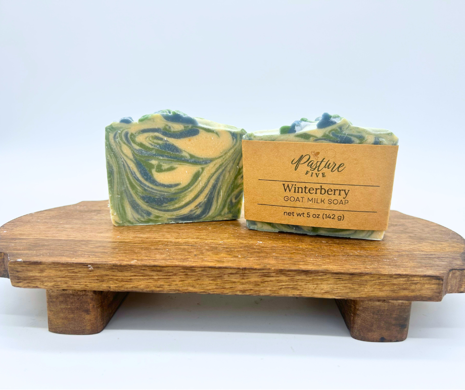 Two bars of Winterberry Goat Milk Soaps. One with a wrap and one with none. 