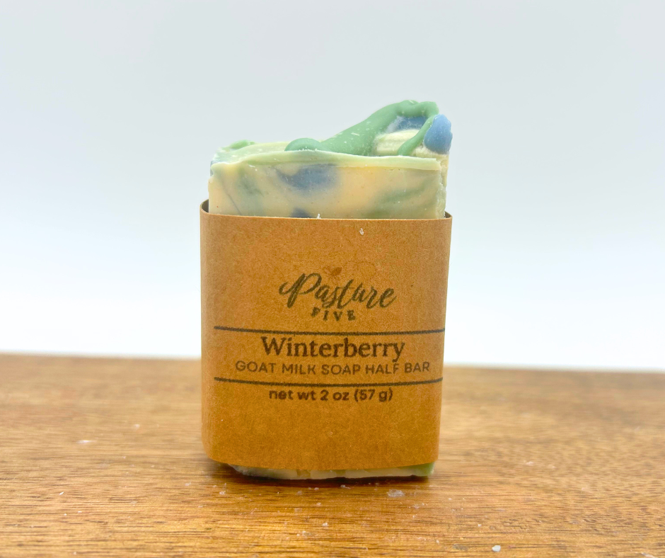 Half Bar of Winterberry Goat Milk Soap on a wood board. 