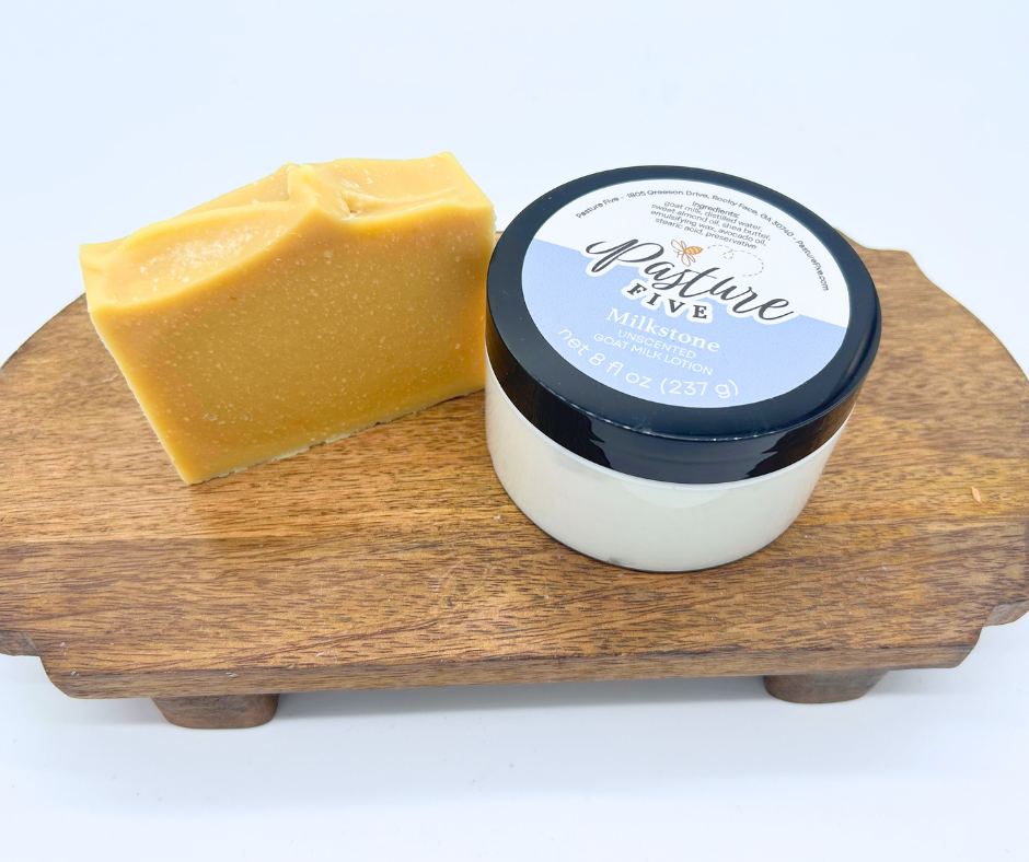 A full size goat milk soap bar and jar of lotion on a wood board. 