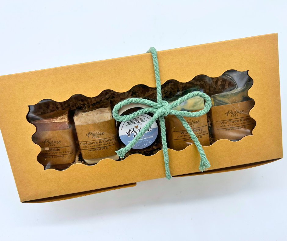 A gift box with 4 half bars and one mini lotion with a bow.